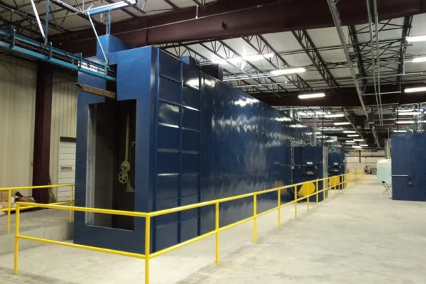 Long blue convection cure oven tunnel behind yellow safety railing