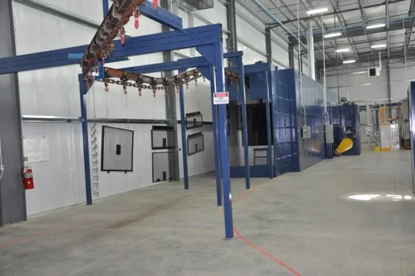 Cure oven with an overhead conveyor carrying racked parts to the entrance